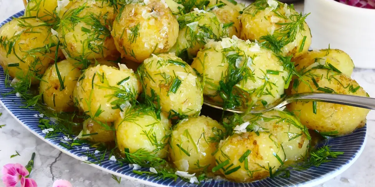 Njut av nykokt färskpotatis med dill och gräslök, en klassiker som visar hur kokar man potatis till perfektion. En svensk flagga vajar stolt.