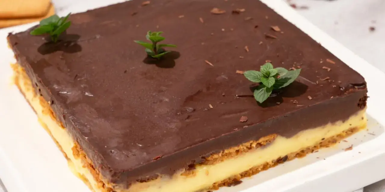 Deliciosa tarta de la abuela con capas de galleta y crema, cubierta de chocolate y decorada con menta fresca.