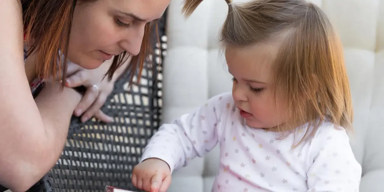 Mama czyta dziecku, a maluch odkrywa świat przez książkę, tworząc własne neologizmy dziecięce.