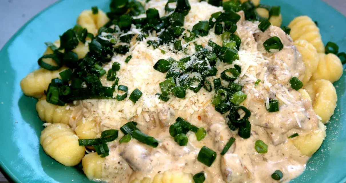 Pyszne gnocchi z kurczakiem w kremowym sosie, posypane parmezanem i szczypiorkiem.