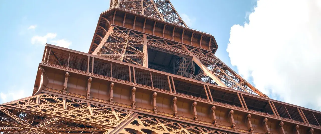 La famille Eiffel, une fortune bâtie sur le fer. Vue rapprochée de la Tour Eiffel, structure métallique complexe sous un ciel bleu.