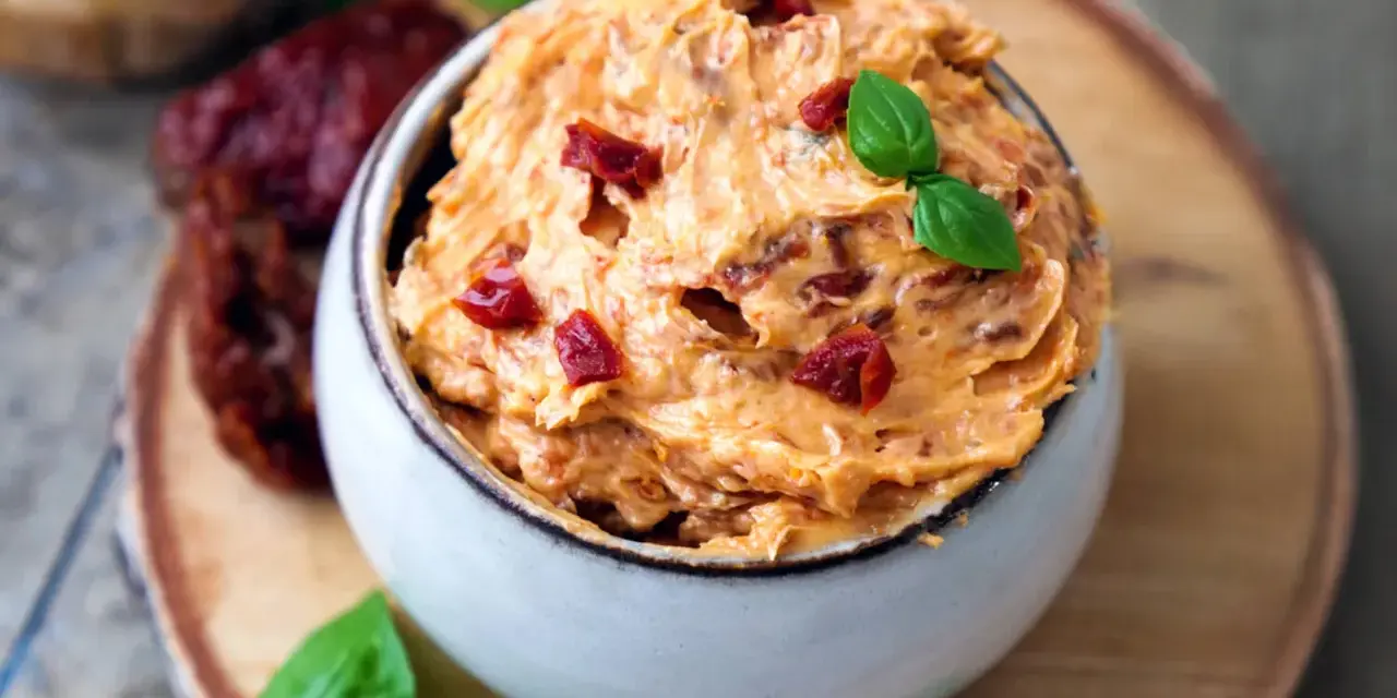 Cremige Tomatenbutter, garniert mit Basilikum und getrockneten Tomatenstücken. Perfekt für ein einfaches Tomatenbutter Rezept.