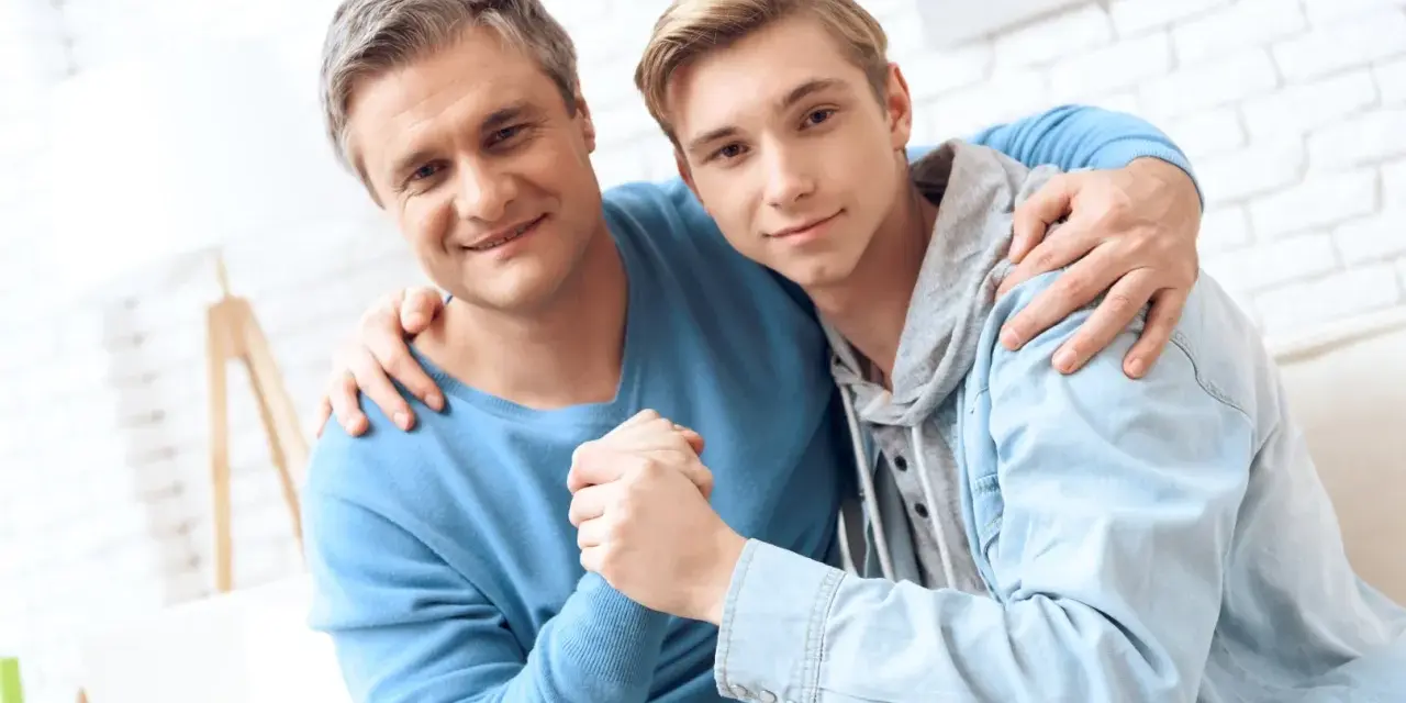 Ojciec obejmuje syna, wspierając go w ważnych życiowych rozmowach.