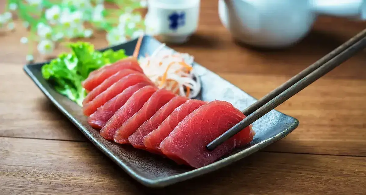Pyszne japońskie ryby, świeże sashimi z tuńczyka, podane z sałatką i sosami. Pałeczki gotowe do degustacji.