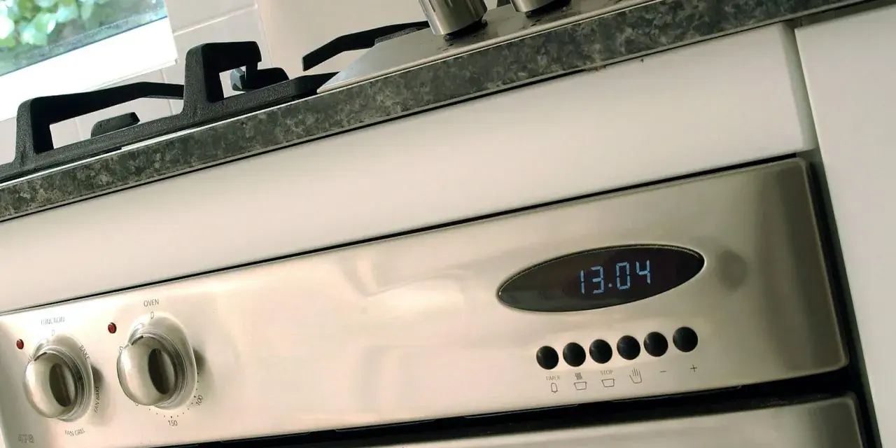 Edelstahl-Backofen mit digitaler Zeitanzeige (13:04). Die Knöpfe für Funktion und Temperatur sind sichtbar. Bereit für den ersten **Backofen einbrennen**.