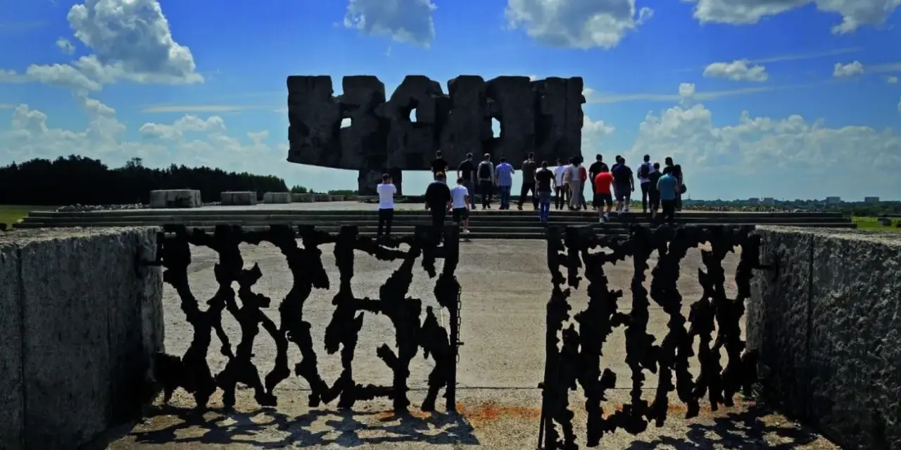 Brama pamięci na terenie byłego obozu Majdanek. Grupa ludzi zwiedza miejsce pamięci.
