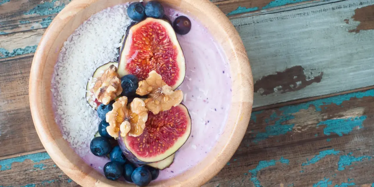 Smoothie bowl z figami, borówkami i wiórkami kokosowymi, przypominający wyglądem tradycyjny kisiel.