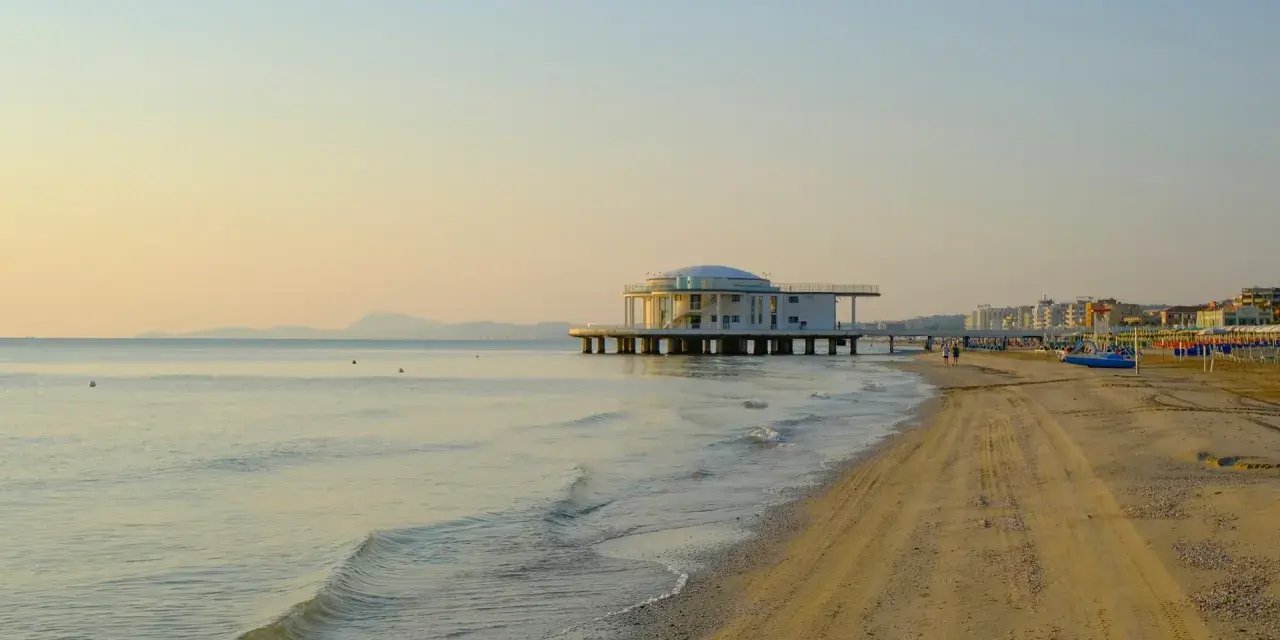 Alba dorata sul mare di Senigallia, con il celebre edificio sul mare e la spiaggia che si estende verso la città.