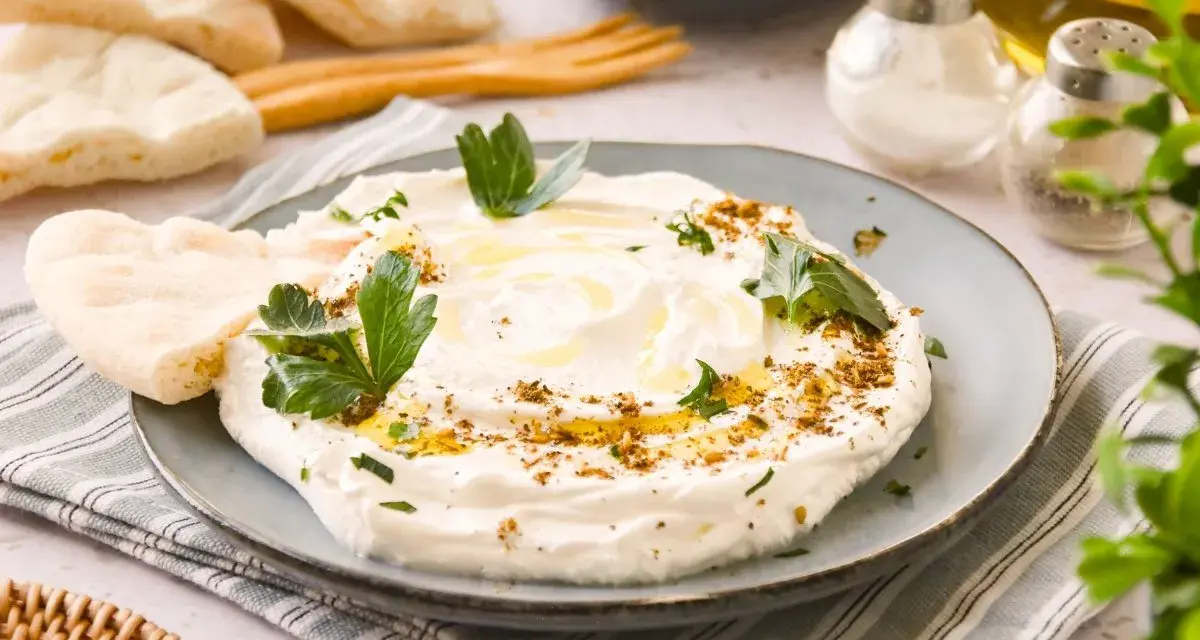 Labneh cremoso con aceite de oliva, za'atar y perejil, servido con pan de pita.