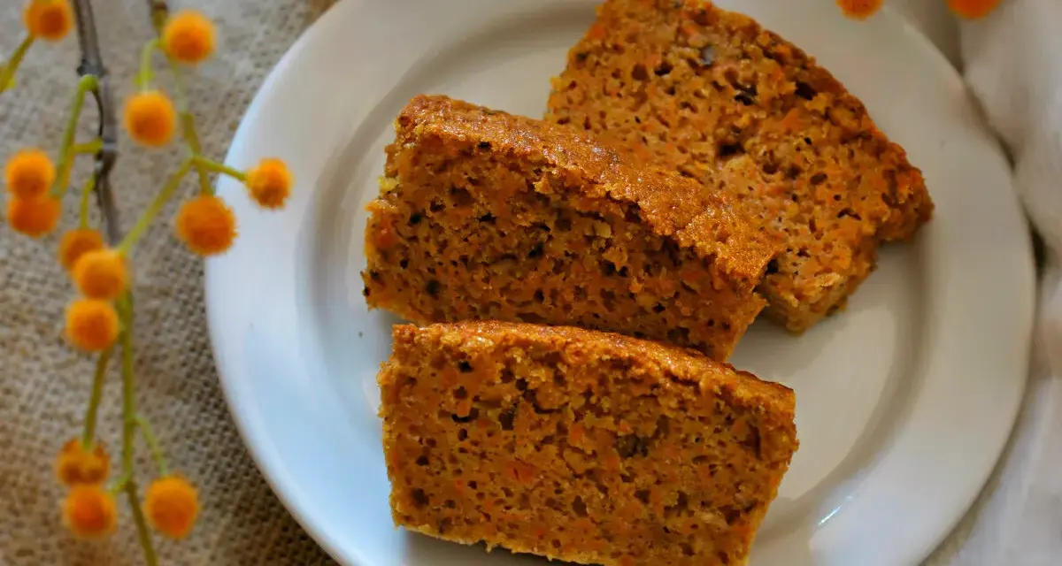 Rebanadas de bizcocho de zanahoria casero, esponjoso y con trocitos de zanahoria visibles, servidas en un plato blanco.