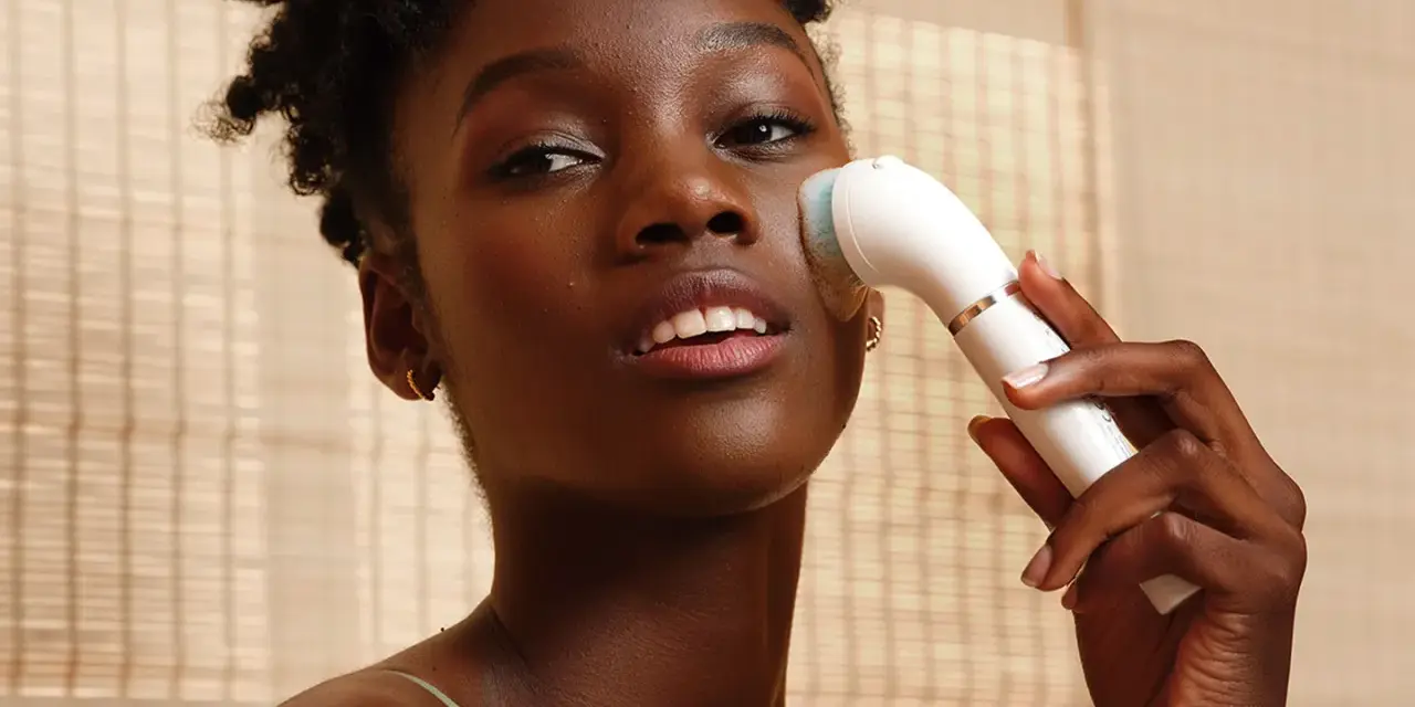 Donna con pelle scura usa un dispositivo per un trattamento esfoliante viso, per una pelle luminosa e pulita.