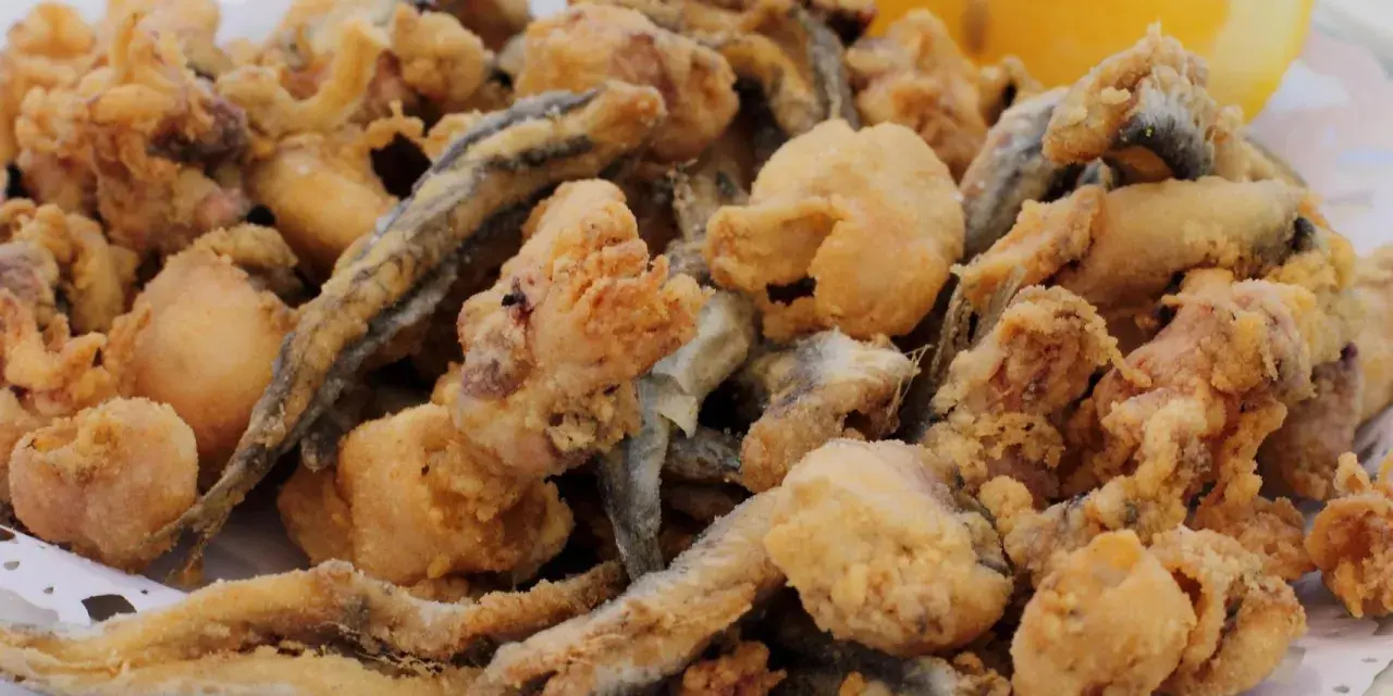 Frito y crujiente pescado en adobo, con trocitos de calamar y una rodaja de limón.