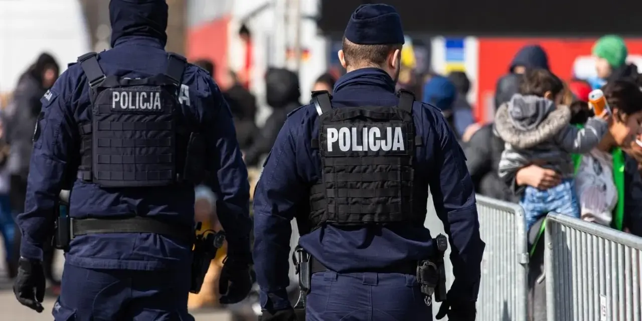 Dwóch policjantów w kamizelkach taktycznych pilnuje porządku. Chcesz wiedzieć, co trzeba zrobić, żeby zostać policjantem?