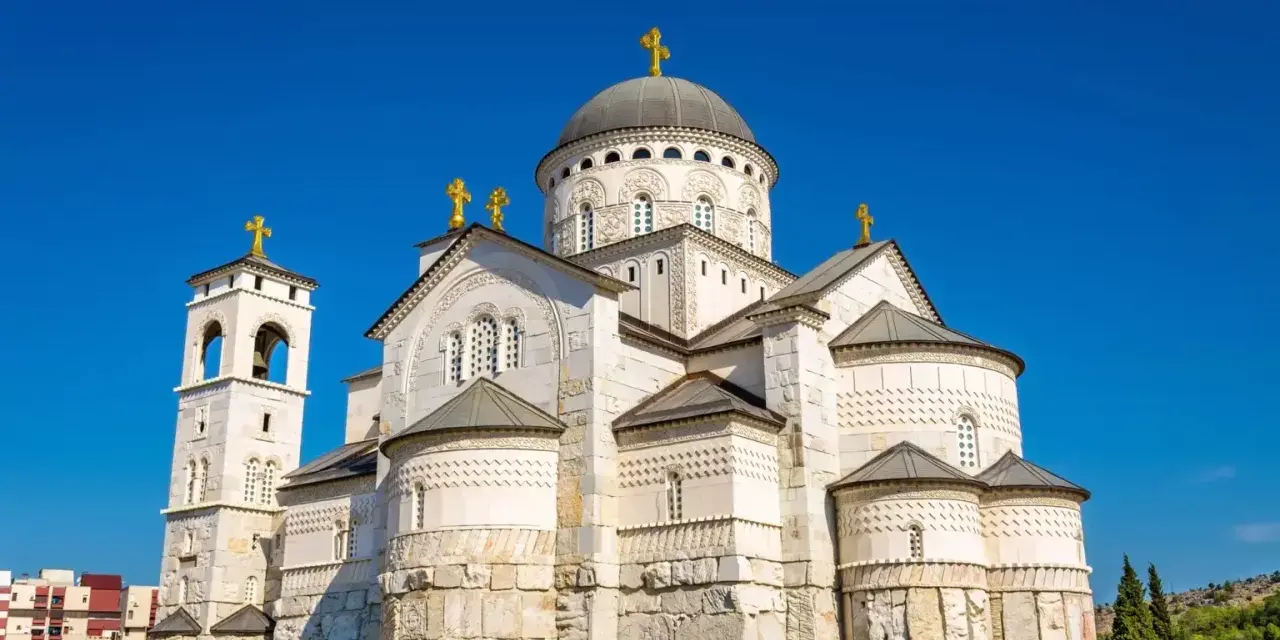 Majestatyczna cerkiew w Podgoricy, jedna z głównych atrakcji miasta, z dominującą kopułą i dzwonnicą na tle błękitnego nieba.