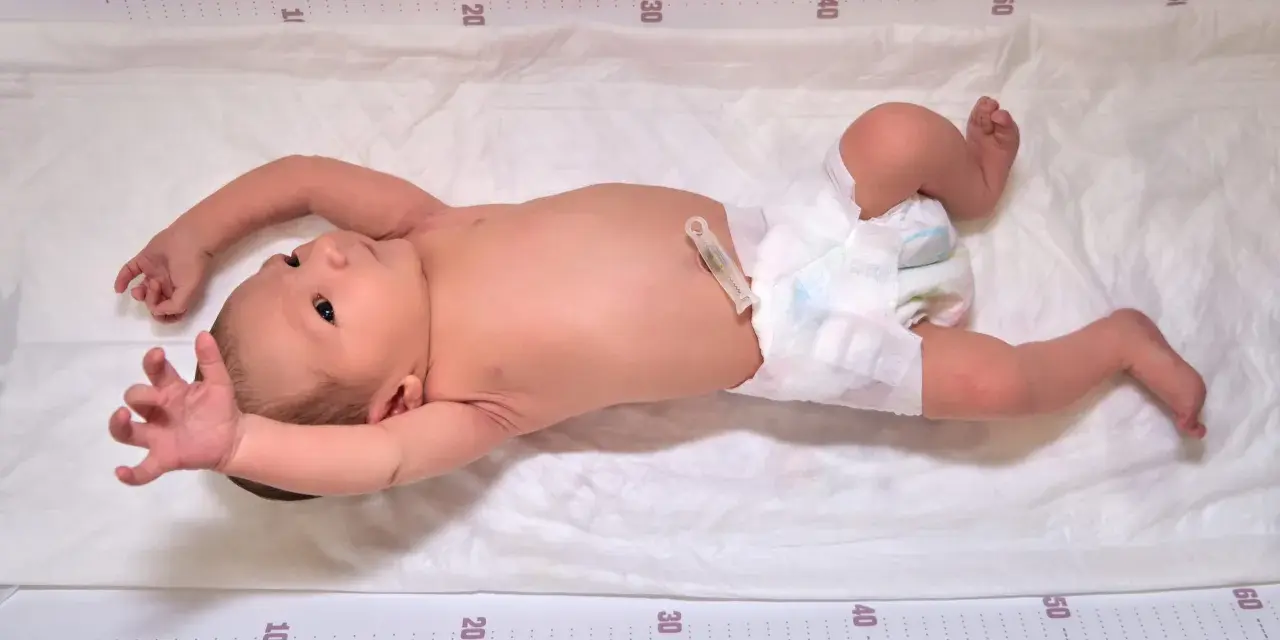 Niemowlę na macie z miarką, wyciąga rączki. Czy to odruch moro, czy objaw padaczki?