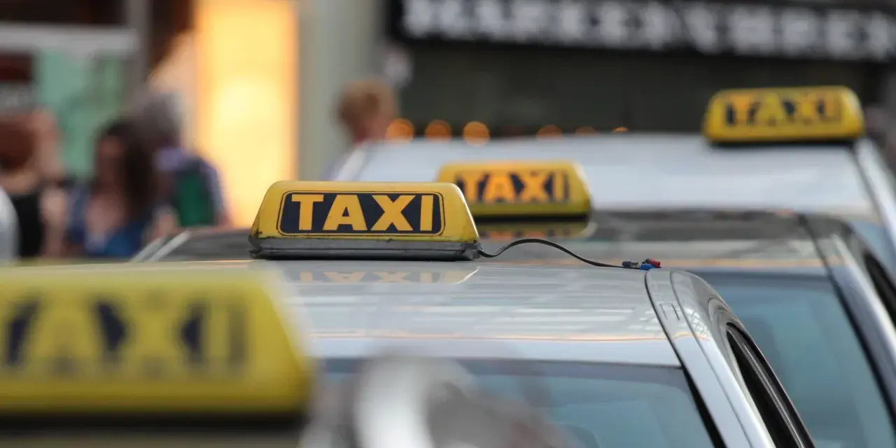 Reihe von Taxis mit gelben Dachschildern. Die aktuellen Taxipreise sind auf den Schildern nicht sichtbar, aber die Fahrzeuge stehen bereit.