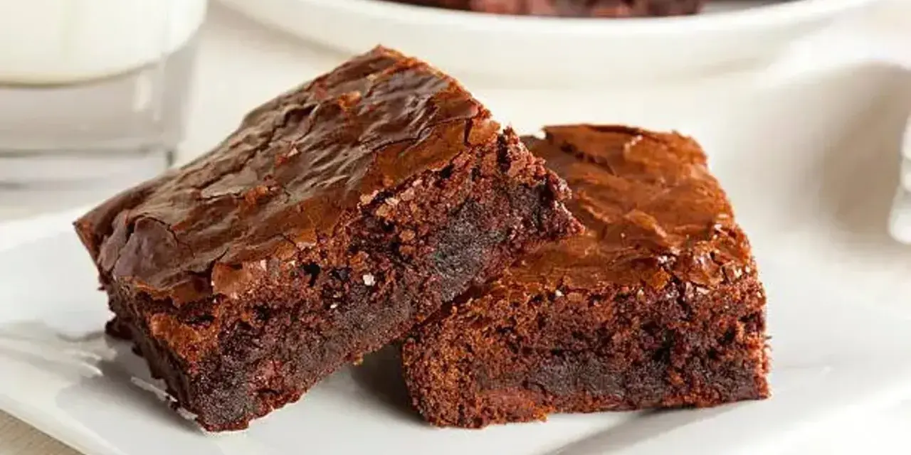 Dos deliciosos trozos de brownie de chocolate, con una textura húmeda y crujiente por encima, listos para ser disfrutados.
