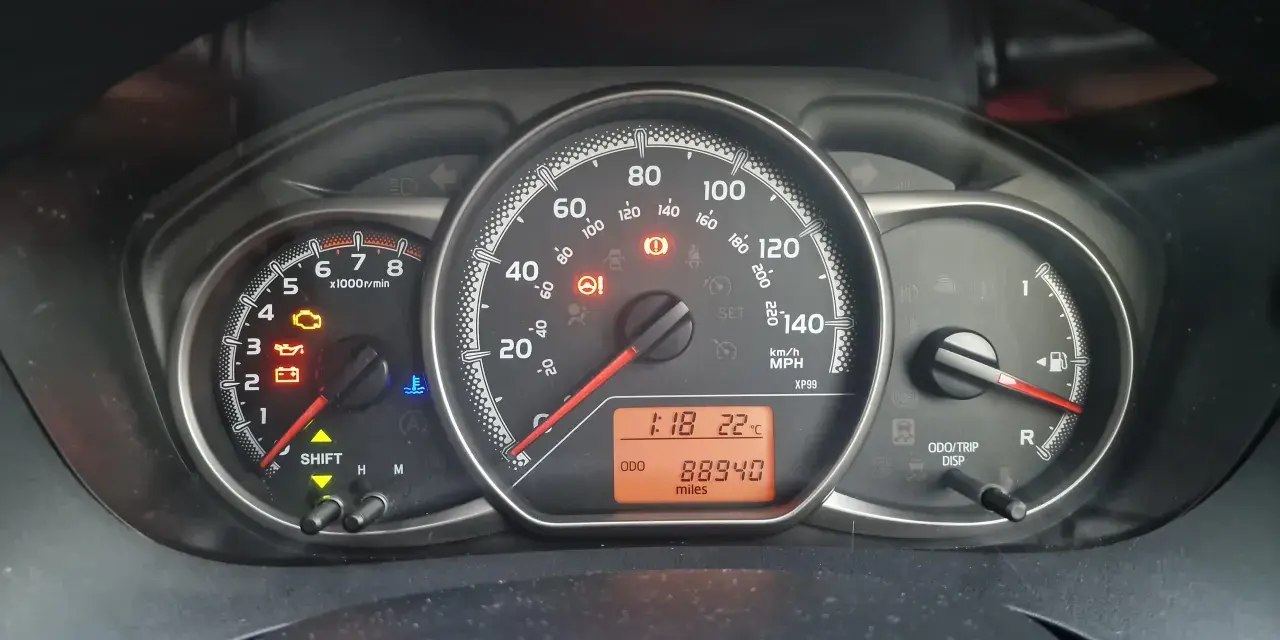 Kontrolka silnika świeci się na desce rozdzielczej Toyoty, wskazując błąd DTC P1604. Odometer pokazuje 88940 mil.