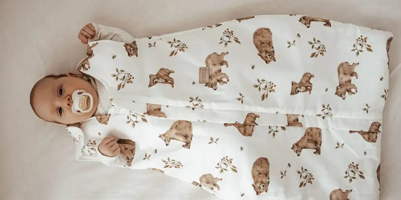 Niemowlę w śpiworku z misiami i pszczołami. Od kiedy kołderka dla niemowlaka jest tak urocza, sen staje się przyjemnością.