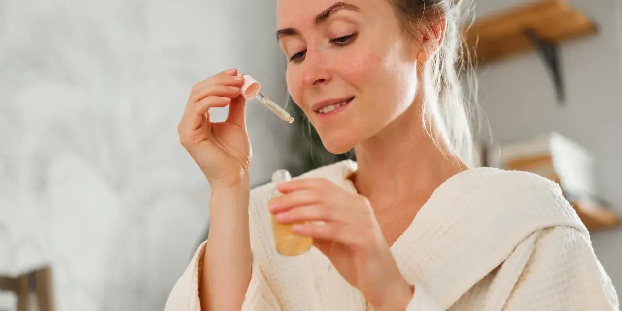 Frau mit einem Tropfen Serum in der Pipette, bereit für ihre Hautpflege-Routine. Ob Retinol oder Hyaluron, sie wählt das Beste für ihre Haut.