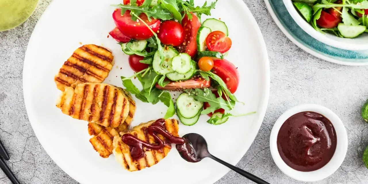 Grillowany ser halloumi z sosem barbecue i świeżą sałatką z pomidorów i ogórków. Idealny pomysł na lekki obiad.
