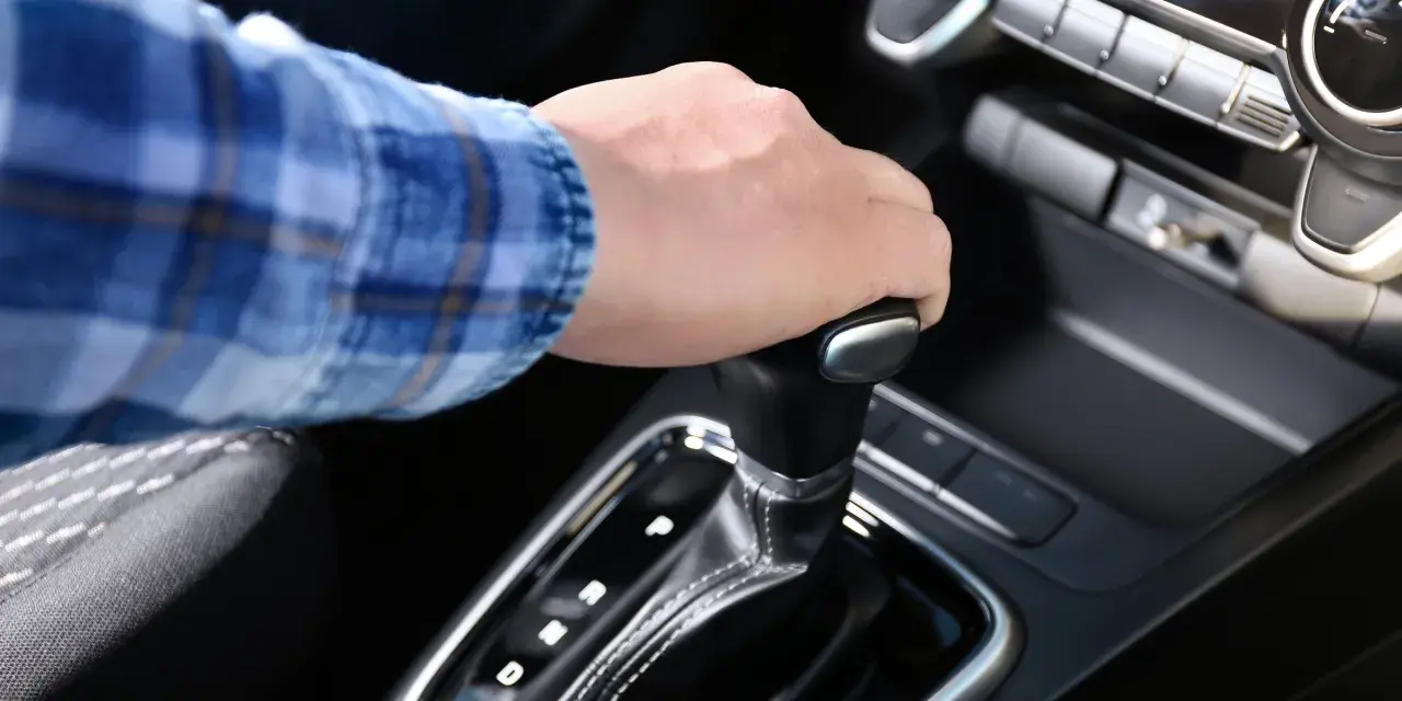 Dłoń na dźwigni zmiany biegów w aucie z funkcją auto hold i manualną skrzynią.