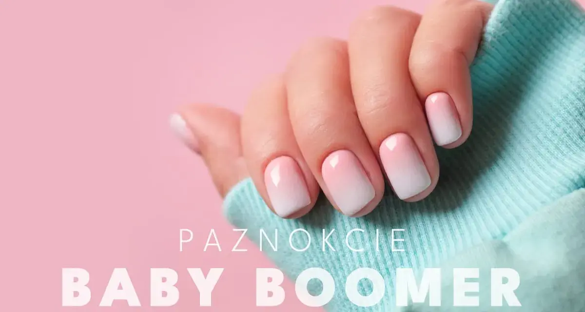Dłoń z paznokciami hybryda baby boomer w delikatnym różowo-białym ombre, na tle pudrowego różu i turkusowego materiału.