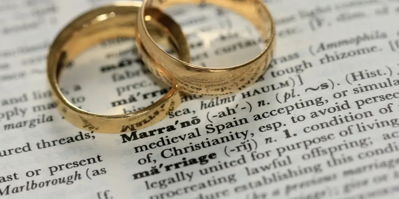 Two gold wedding rings rest on a dictionary page, highlighting the definition of "marriage" and its contrast to sexual immorality.