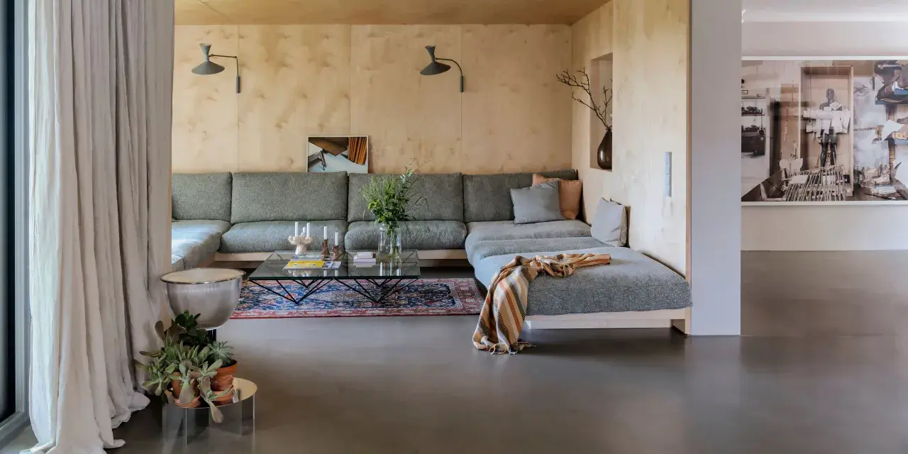 Sofá modular gris, alfombra oriental, mesa de centro de cristal y detalles de interiorismo años 60.