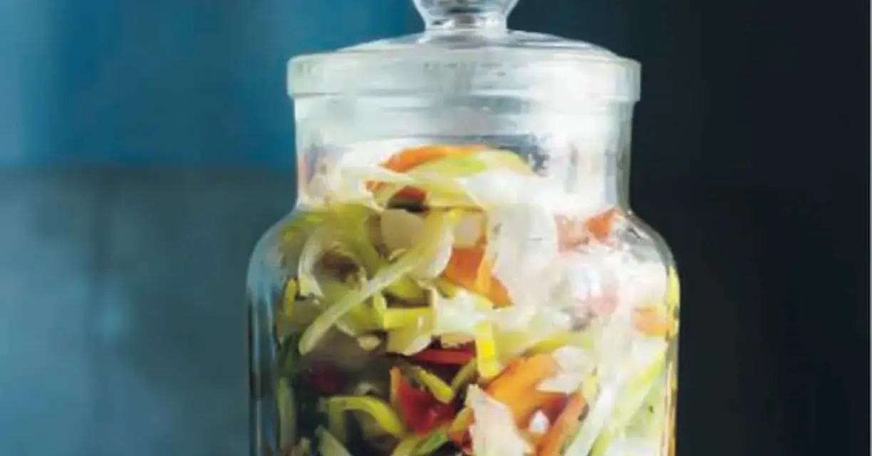 En glasburk fylld med strimlad vitkål, morötter och purjolök, redo för en 3 veckors sallad.