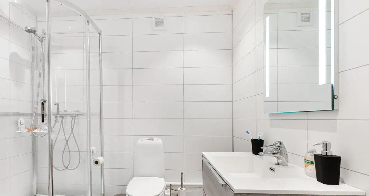 Baño moderno con ducha, inodoro y lavabo. La ventilación del baño es discreta en la pared, asegurando un ambiente fresco.