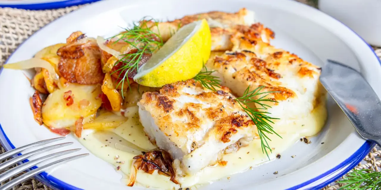 Gebratener Fisch mit Bratkartoffeln und Zwiebeln, garniert mit Dill und Zitrone. So sieht leckerer Pannfisch aus!
