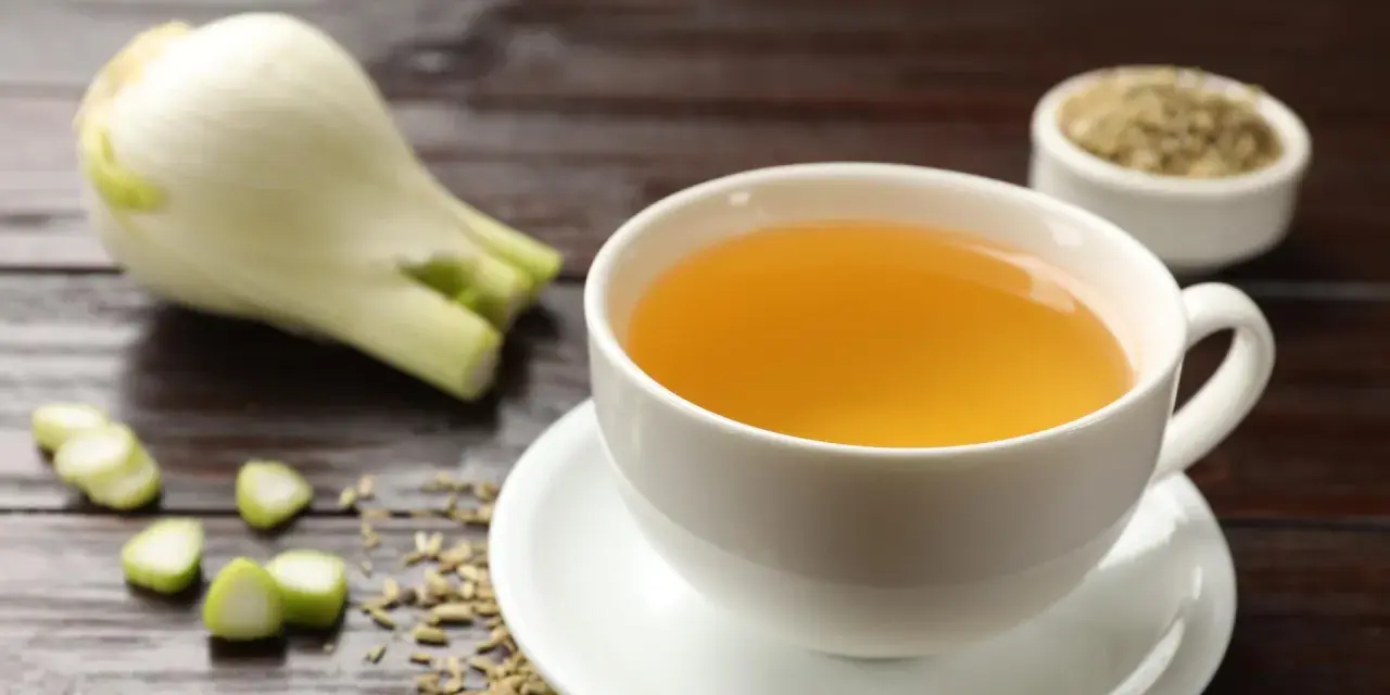 Una taza de infusión de hinojo por la noche, con hinojo fresco y semillas esparcidas.