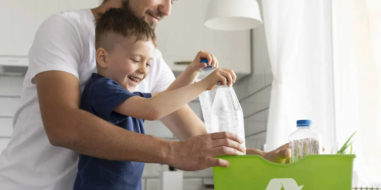 Padre e hijo reciclando botellas de plástico en un contenedor verde. Enseñando conciencia ecológica desde pequeños.