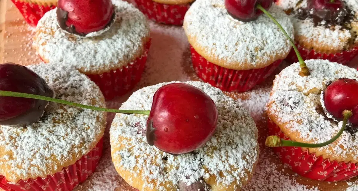 Saftige kirsch muffins, bestäubt mit Puderzucker und garniert mit frischen Kirschen. Ein süßer Genuss!