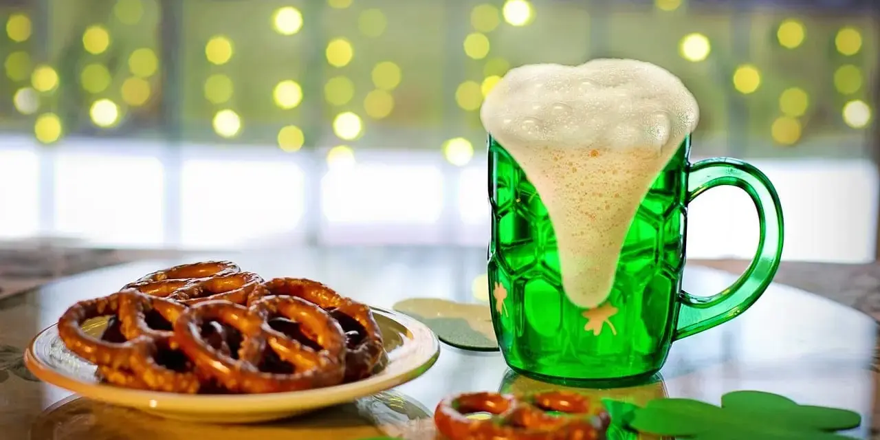 Zielony kufel z pianą i talerz precli. Zastanawiasz się, ile kalorii ma precel?