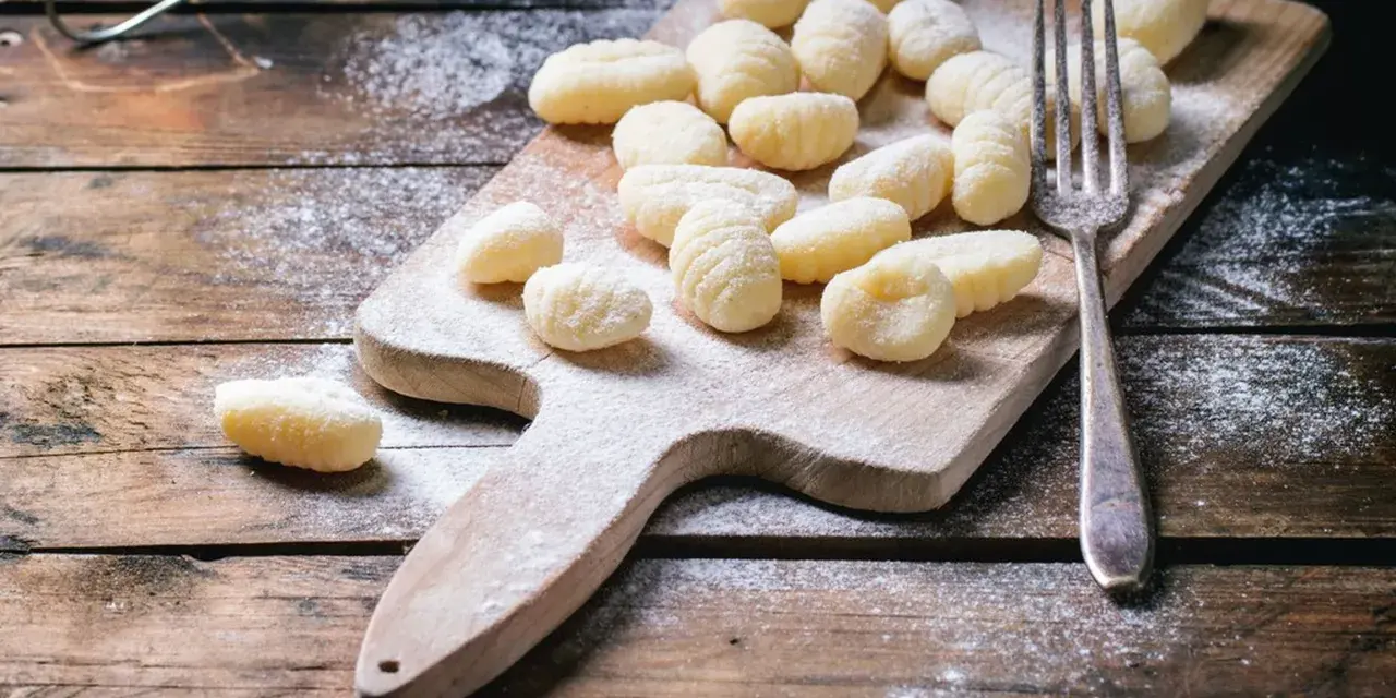 Gnocchi fatti in casa su tagliere di legno, spolverati di farina. L'impasto gnocchi troppo appiccicoso ha reso la preparazione un po' complicata, ma il risultato è invitante.