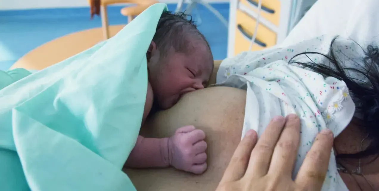 Neugeborenes Baby an der Brust der Mutter, ein Moment der stillen Geburt und des ersten Kontakts.