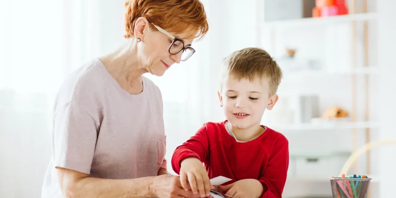Babcia pomaga wnuczkowi w zajęciach, które mogą być częścią terapii stereotypii ruchowych.
