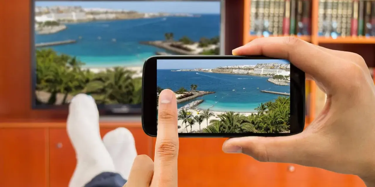 Jak podłączyć telefon do telewizora przez HDMI? Widok na plażę z palemami na ekranie telefonu i telewizora.