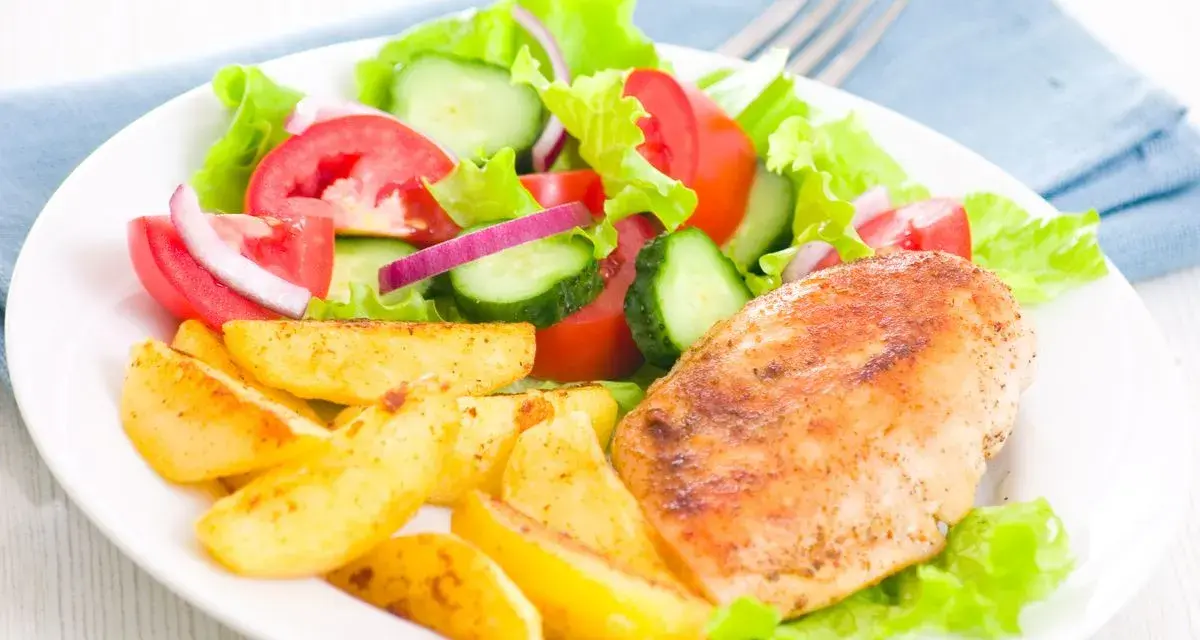 Petto di pollo in friggitrice ad aria, patate arrosto e insalata fresca con pomodori, cetrioli e cipolla rossa.