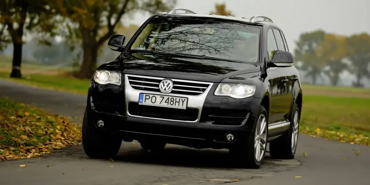 Czarny VW Touareg 2.5 TDI R5 na jesiennej drodze. Choć to solidne auto, warto znać jego potencjalne wady.