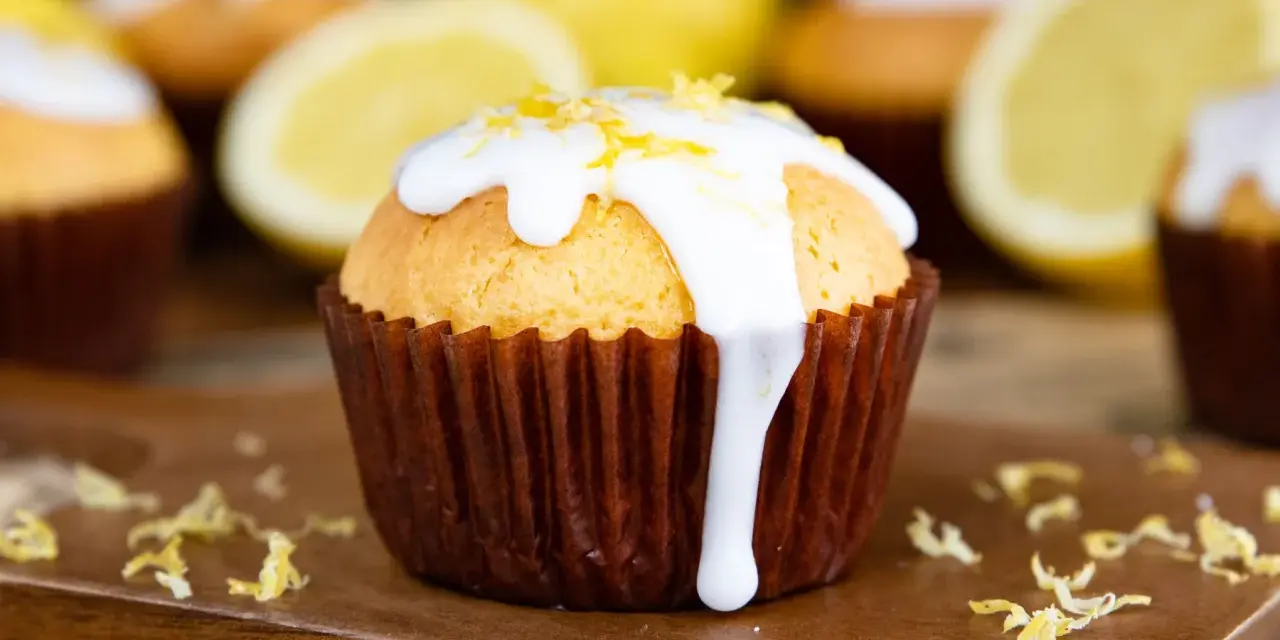 Zitronenmuffins mit weißer Glasur und Zitronenschale, die an eine Backmischung für Zitronenmuffins erinnern.
