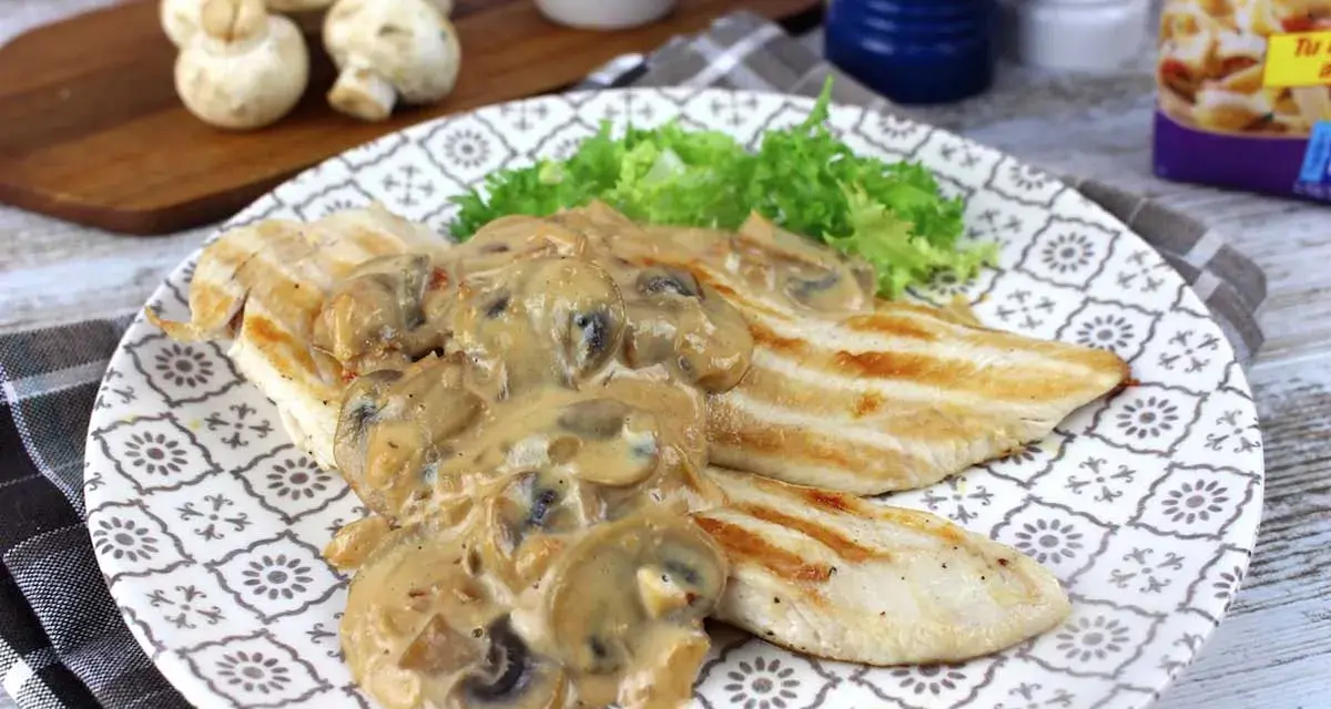 Sabroso pollo con champiñones en salsa cremosa, servido con lechuga fresca en un plato decorado.