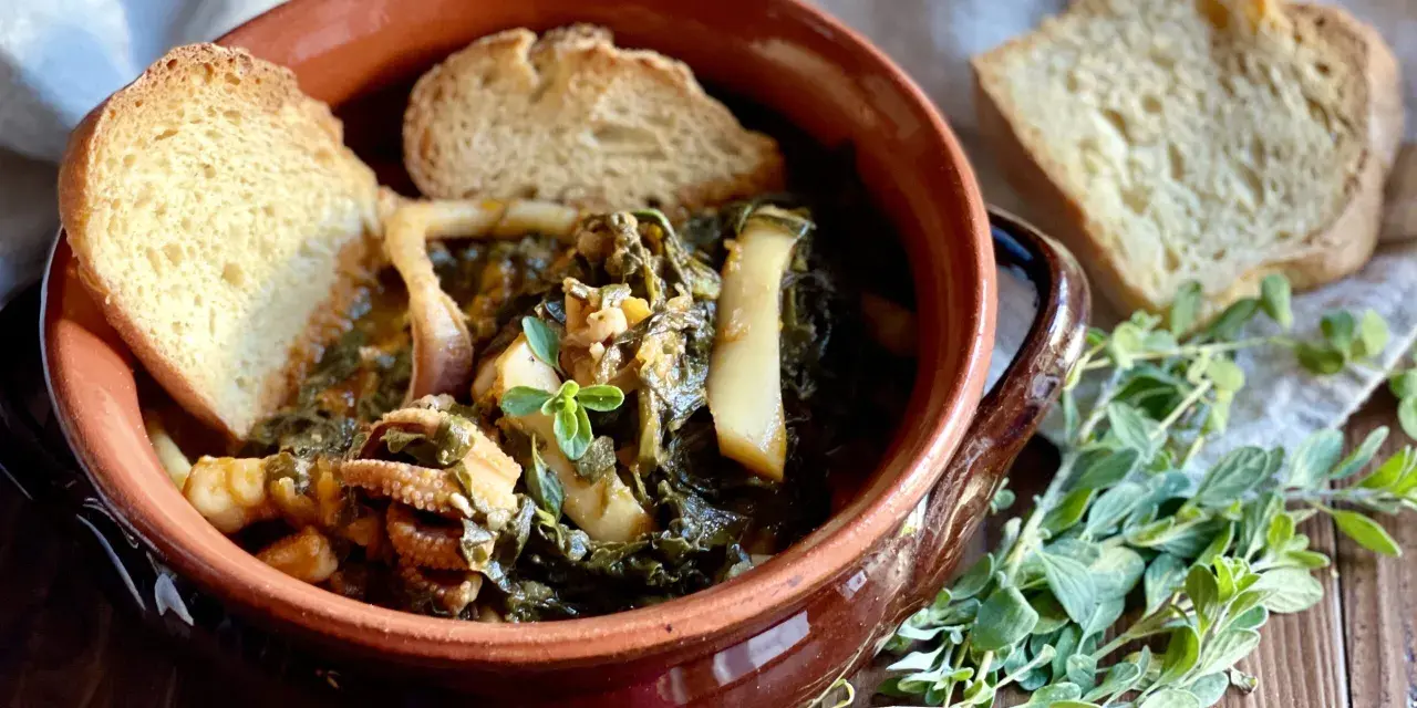 Seppie in zimino, un piatto tradizionale con seppie tenere e verdure, servito in una ciotola di terracotta con pane tostato e erbe aromatiche.