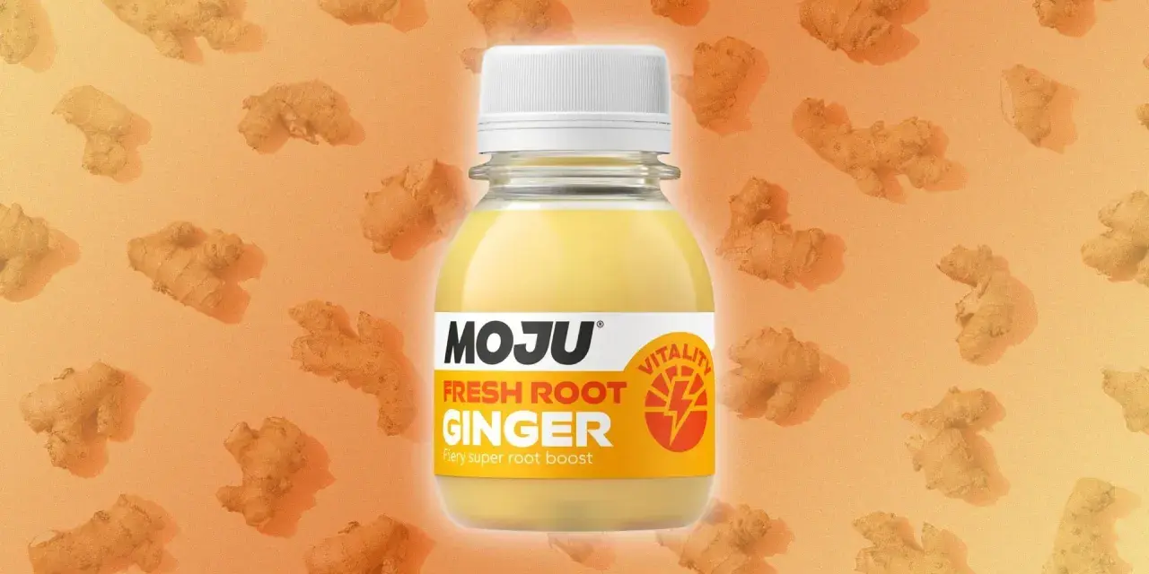 Botella de MOJU con shots de jengibre fresco, rodeada de raíces de jengibre. Un impulso de vitalidad.