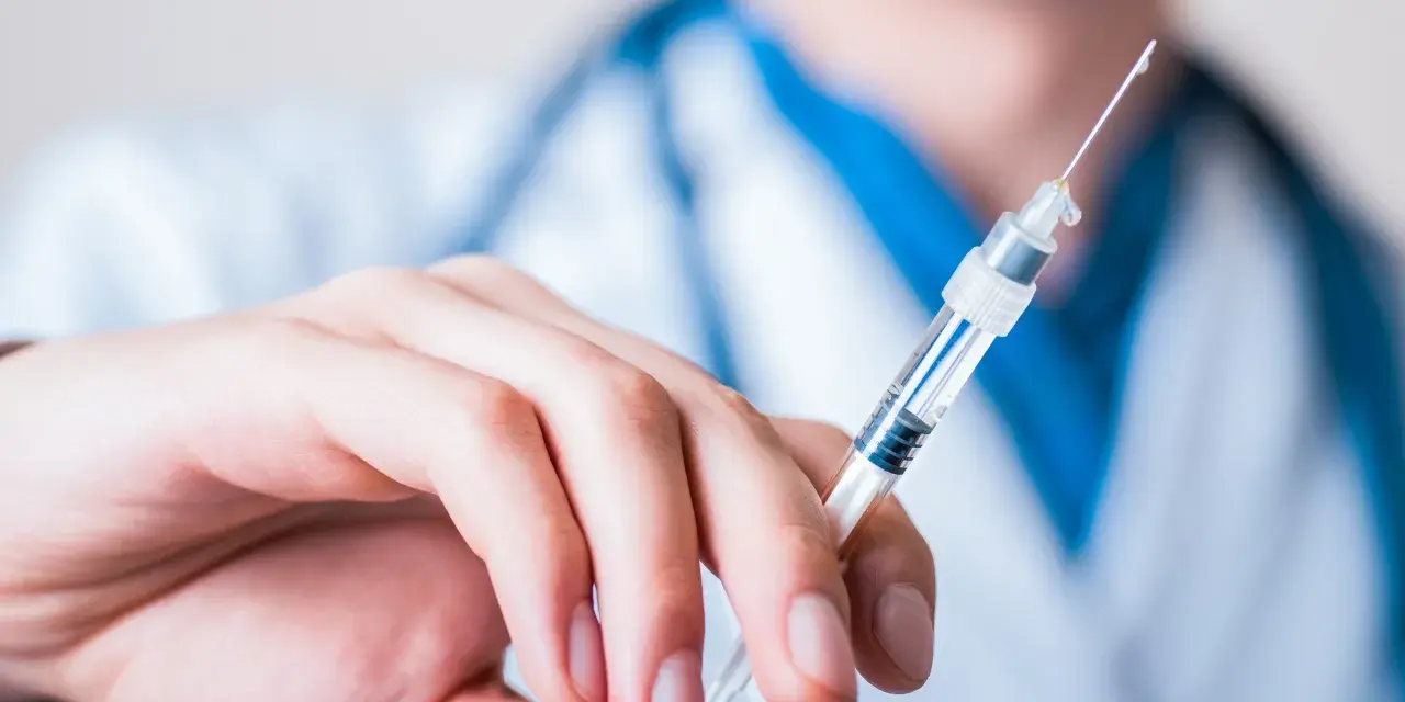 Dłoń trzymająca strzykawkę z heparyną. Pytanie: gdzie wyrzucić strzykawki po heparynie? Bezpieczne utylizowanie jest kluczowe.