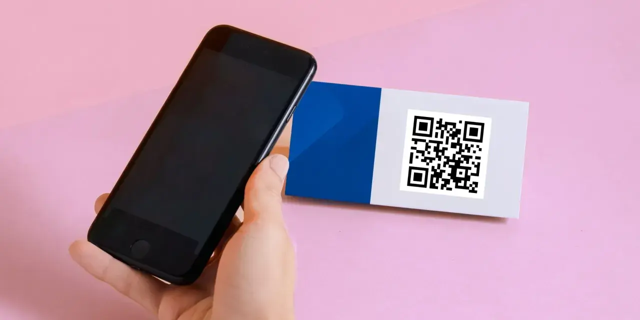 En hand håller en iPhone 6 för att scanna en QR-kod på ett kort med blått och vitt.