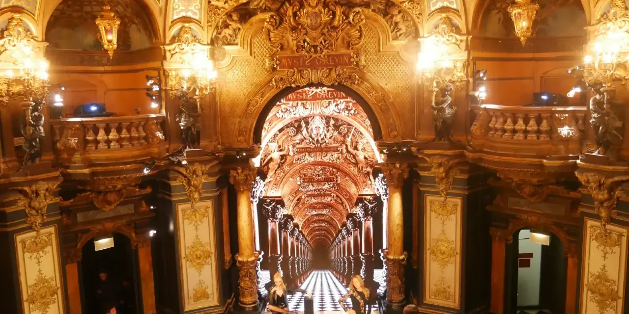 L'intérieur doré et orné du musée Grévin à Paris, avec des statues de cire et un sol à damier.