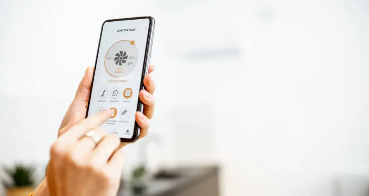 Mano usando un smartphone para encender calefacción a distancia en la sala de estar.